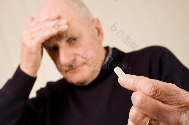 头痛的老人拿着药片或药丸
