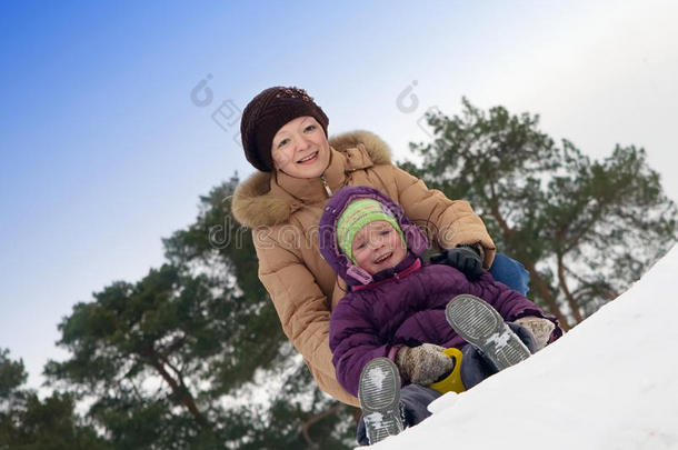 带着小孩的母亲在雪地里滑来滑去