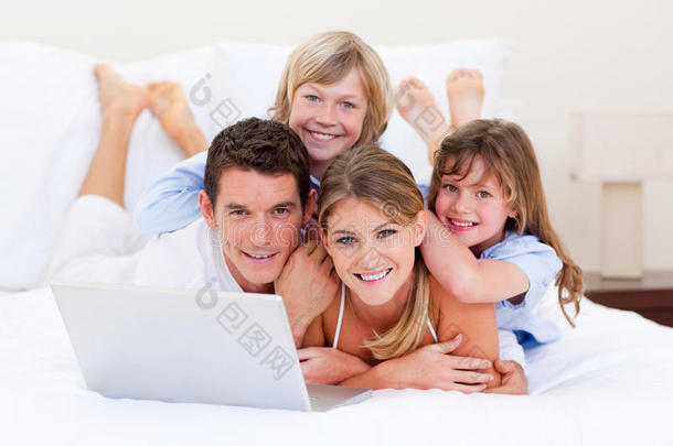 微笑的家人看着躺在床上的笔记本电脑