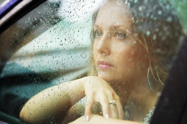 一个悲伤的年轻女人坐在车里<strong>看</strong>着<strong>窗外</strong>
