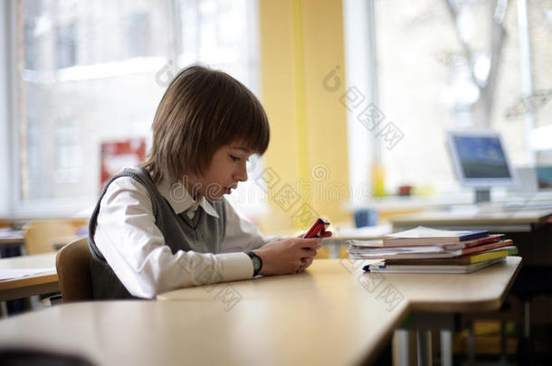小学生拿着手机坐在学校里