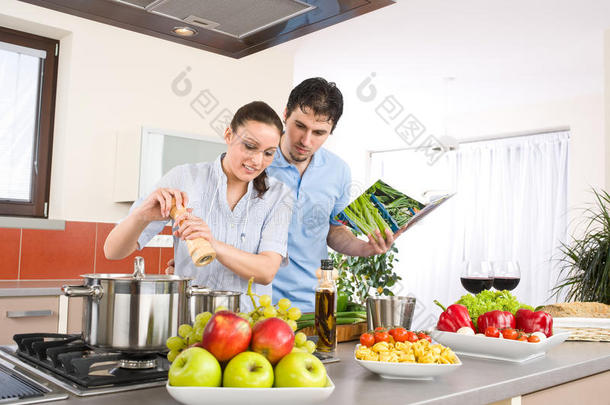 年轻幸福的夫妻在厨房用菜谱做饭