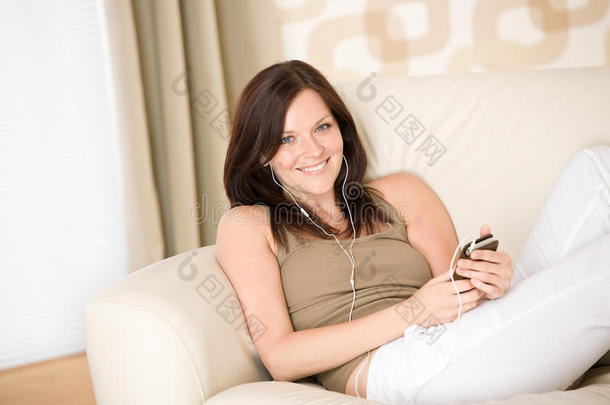 抱着音乐播放器在家沙发上听音乐的女人