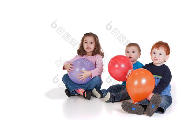 三个孩子坐在派对气球旁