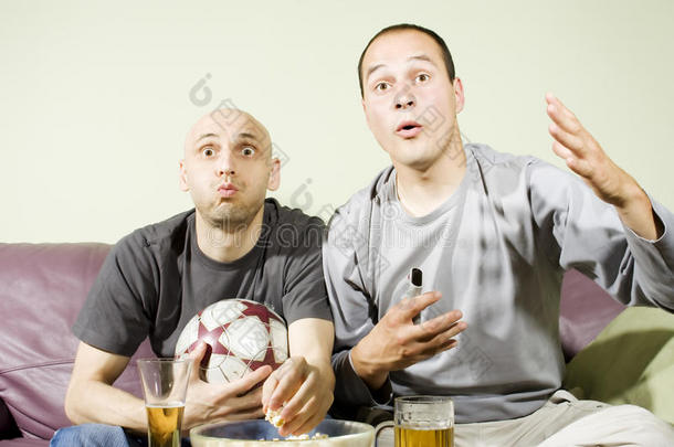 两个年轻人在电视上看足球赛