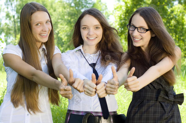 公园里三个竖起大拇指的学生女孩