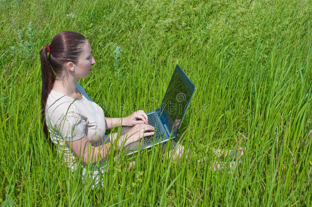 漂亮的女孩在户外用笔记本电脑消夏