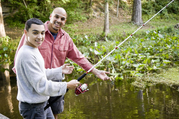 西班牙裔少年和父亲在池塘钓鱼