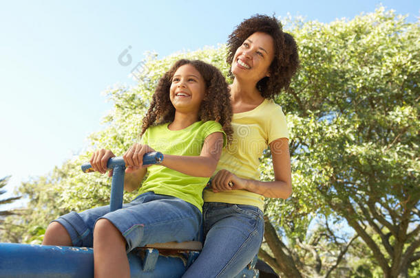 母亲和女儿在公园里骑跷跷板