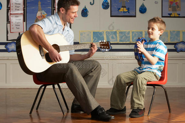 男教师与<strong>学生在教室里</strong>弹吉他