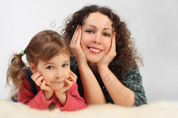 女孩和她带着露齿微笑的母亲躺在床上