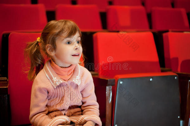 在电影院坐在扶手椅上微笑的小女孩