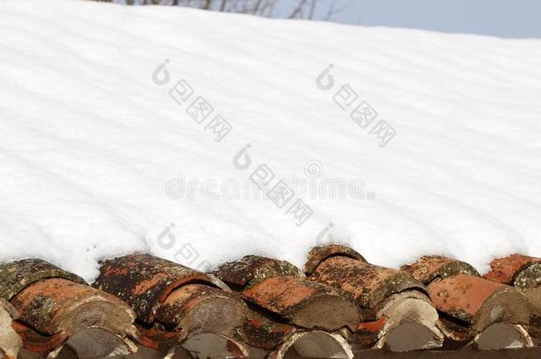年迈的粘土屋顶瓦在冬雪中下雪