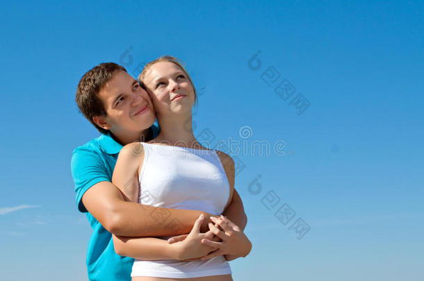 一对年轻夫妇拥抱在一起，仰望天空