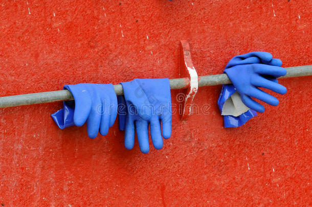 蓝色手套靠在红墙上