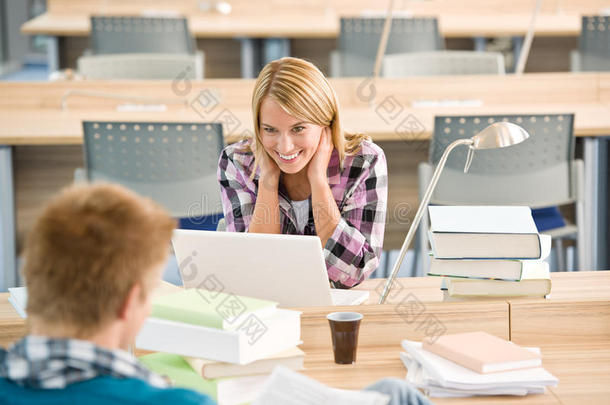 两个<strong>学生在教室里</strong>拿着书和笔记本电脑