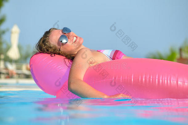 年轻女子在粉红色的<strong>气垫</strong>床上游泳