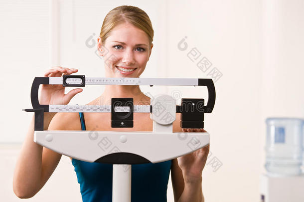 健身俱乐部的一位妇女在秤上<strong>称体重</strong>