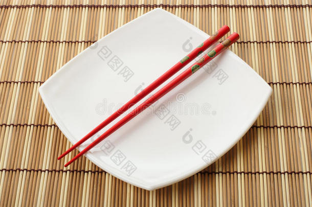 红筷子和白盘子放在竹餐巾上