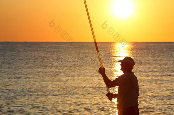 人拿着钓竿和鱼站在岸上