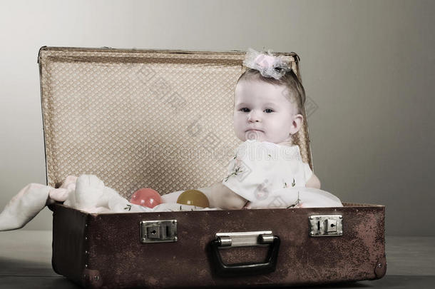小女孩坐在手提箱里。