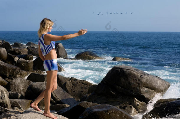 迷人的女孩在海边岩石海滩放松。