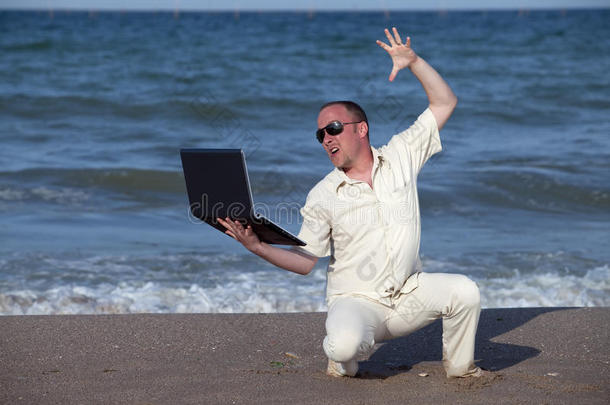 愤怒的男人在海滩上打<strong>笔记本</strong>电脑