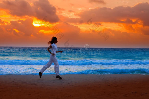 女人的剪影，在夕阳下沿着海洋奔跑