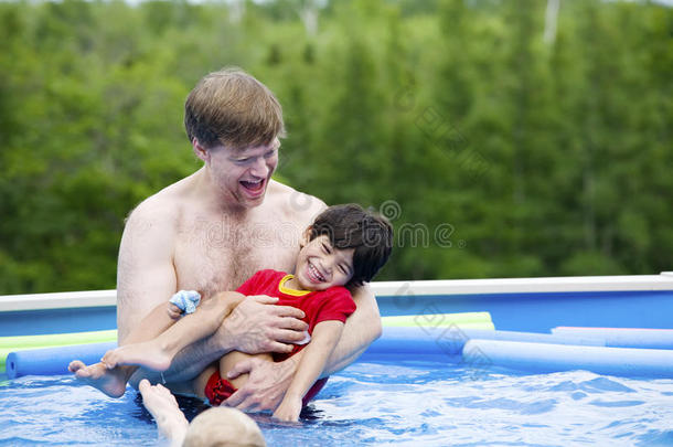 父亲抱着残疾儿子在游泳池里