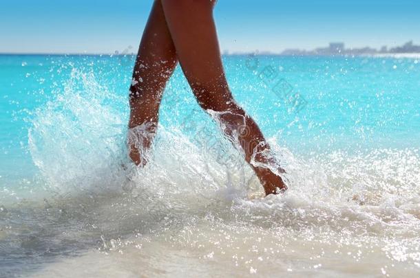 女人的腿走着溅着海滩水