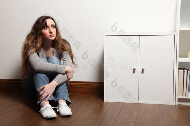 焦虑的少女独自坐在家里的地板上
