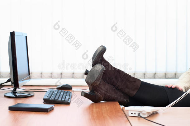 女人穿靴子的脚放在桌面上