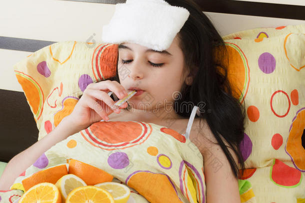 生病的年轻女孩躺在床上拿着温度计