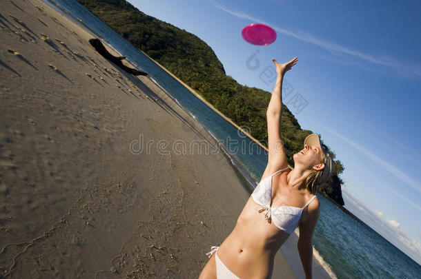 穿比基尼的女孩在热带海滩上抓飞盘