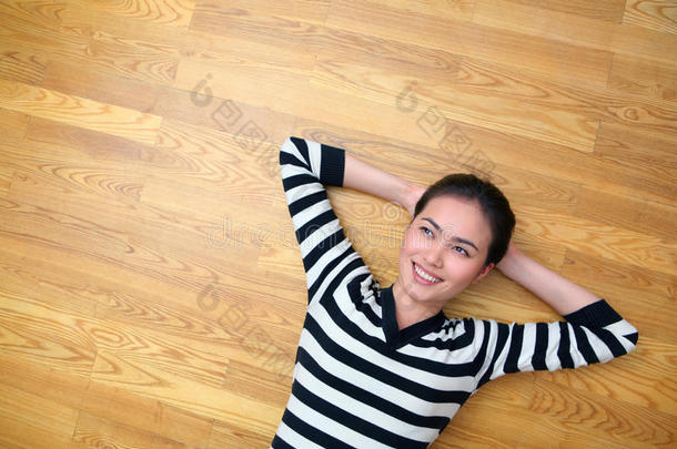 快乐的年轻女子躺在木地板上抬头看