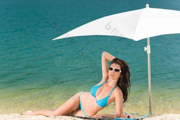 遮阳伞下的夏日海滩女式蓝色比基尼