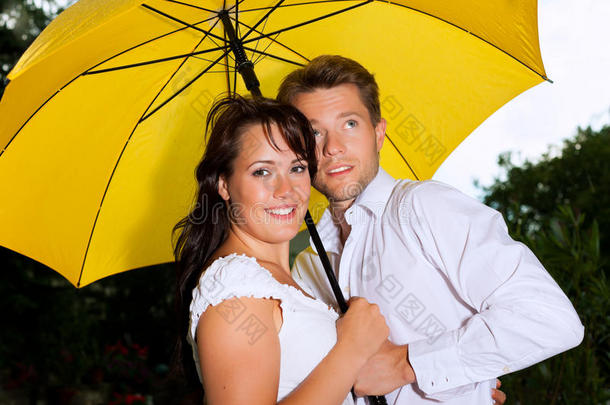 夏日雨中带着雨伞的幸福夫妻