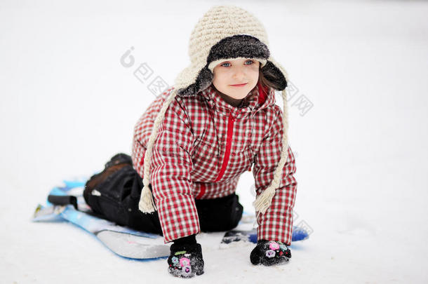 可爱的小女孩在雪地里用碟子滑雪