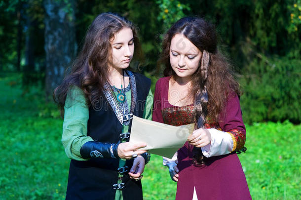 两个穿着中世纪服装的年轻妇女在看报纸