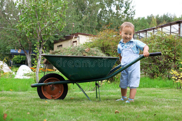 小男孩在花园里推着手推车