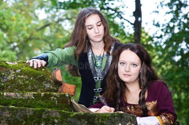 两个穿着中世纪服装的年轻妇女在写论文