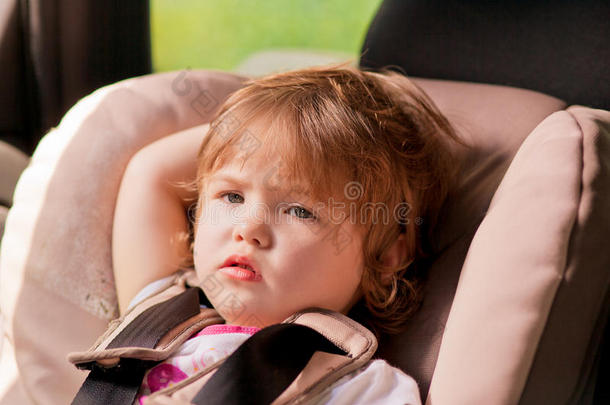 坐在安全座椅上的不快乐的孩子的画像