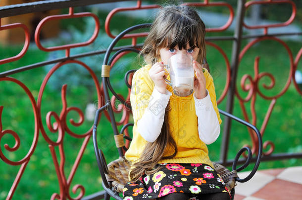 可爱的小女孩坐在户外喝茶