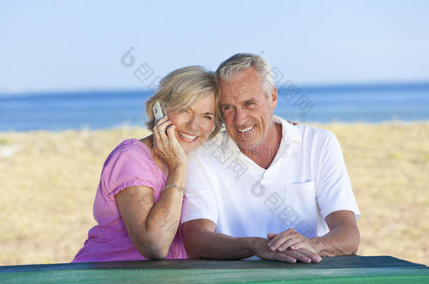 一对老夫妇在海边用手机吃饭