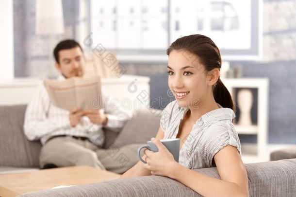 坐在家沙发上微笑的年轻夫妇