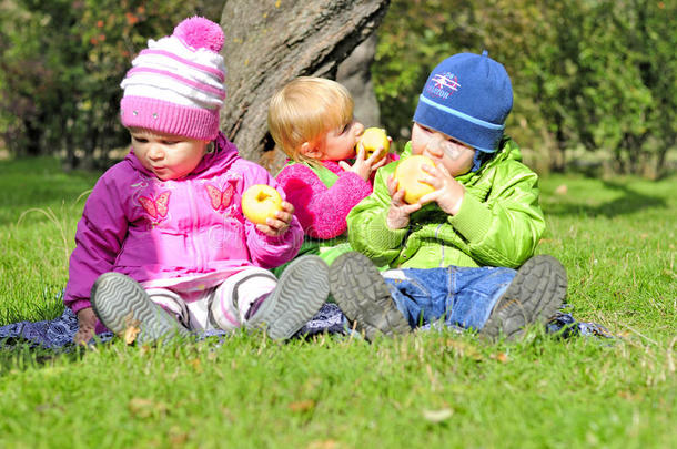 三个小孩坐在绿地上