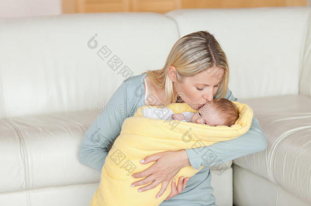 可爱的妈妈亲吻裹在<strong>被子</strong>里的宝宝