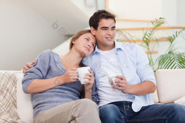 可爱的情侣边喝茶边看电视