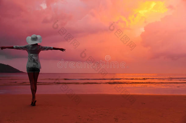 戴帽子的女人站在沙滩上湿漉漉的沙滩上