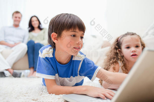 孩子们在地毯上和后面的父母玩电脑游戏